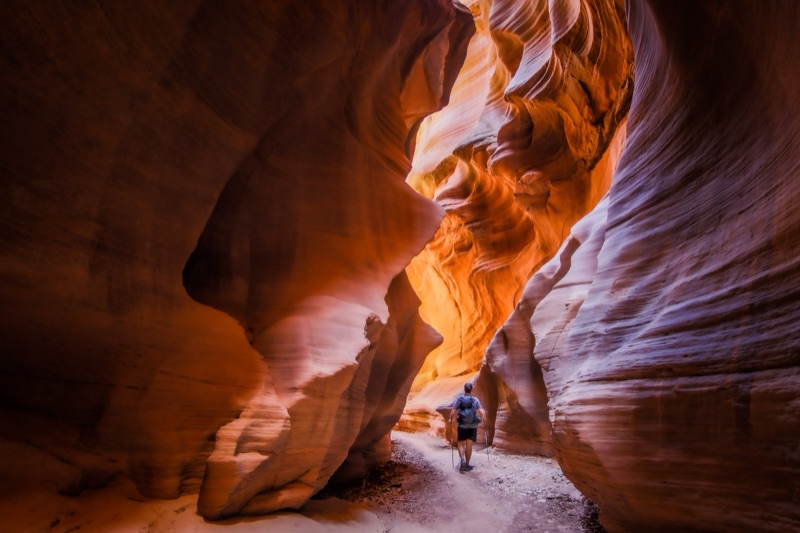 Hiker with trekking poles in the glowing narrows of Buckskin Gulch