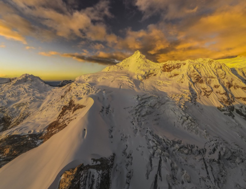Snow peak above a cloud bank in soft pink evening light