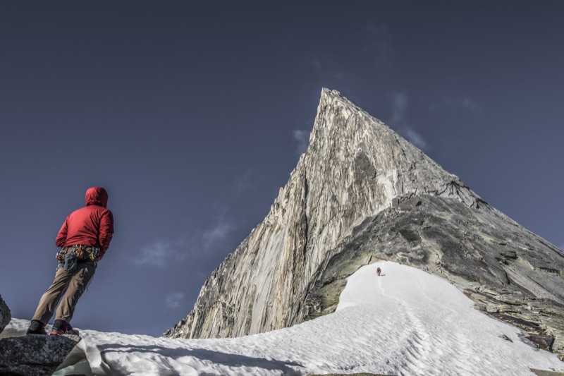 Climber looking up at a granite spire from a snow ridge
