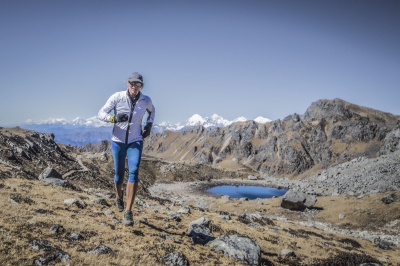 Trail runner crossing alpine tundra with Himalayan peaks on the horizon